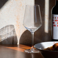 Verre à vin Harmony 35 transparent posé sur une table à côté d'une bouteille de vin