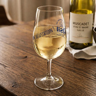 Verre INAO sérigraphié en bleu, rempli de vin blanc à côté d'une bouteille de muscadet