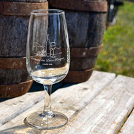 Verre INAO sérigraphié au nom d'un domaine viticole, devant un tonneau