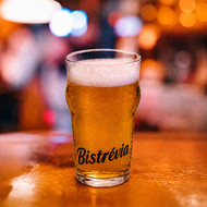Verre Nonic 28,5 sérigraphié au nom d'un bistrot, rempli de bière blonde