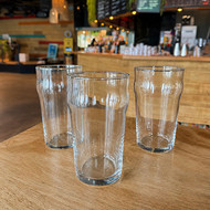 Trois pintes Nonic 56 vierges posées devant le comptoir d'un bar