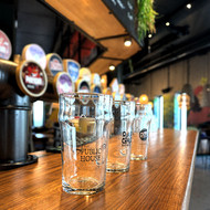 Trois pintes Nonic 56 sérigraphiées au logo de brasseries, alignées sur un comptoir
