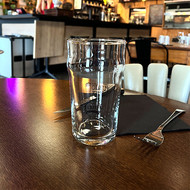 Pinte Nonic 56 sérigraphiée au logo d'un pub, posée sur une table