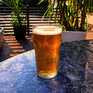 Pinte Nonic 56 sérigraphiée au logo d'un pub, remplie de bière blonde en terrasse