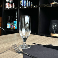 Verre Pilsener vierge dressé sur une table de restaurant