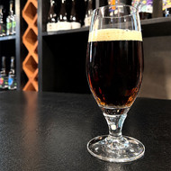 Verre Pilsener sans marquage rempli de bière brune dans une cave à bières