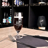Verre Pilsener sérigraphié au logo d'un restaurant, rempli de bière brune