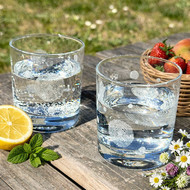 Deux verres Oria gravés remplis d'eau sur une table de jardin
