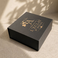 Boîte cadeau carrée noire marquée du logo doré d'un domaine viticole